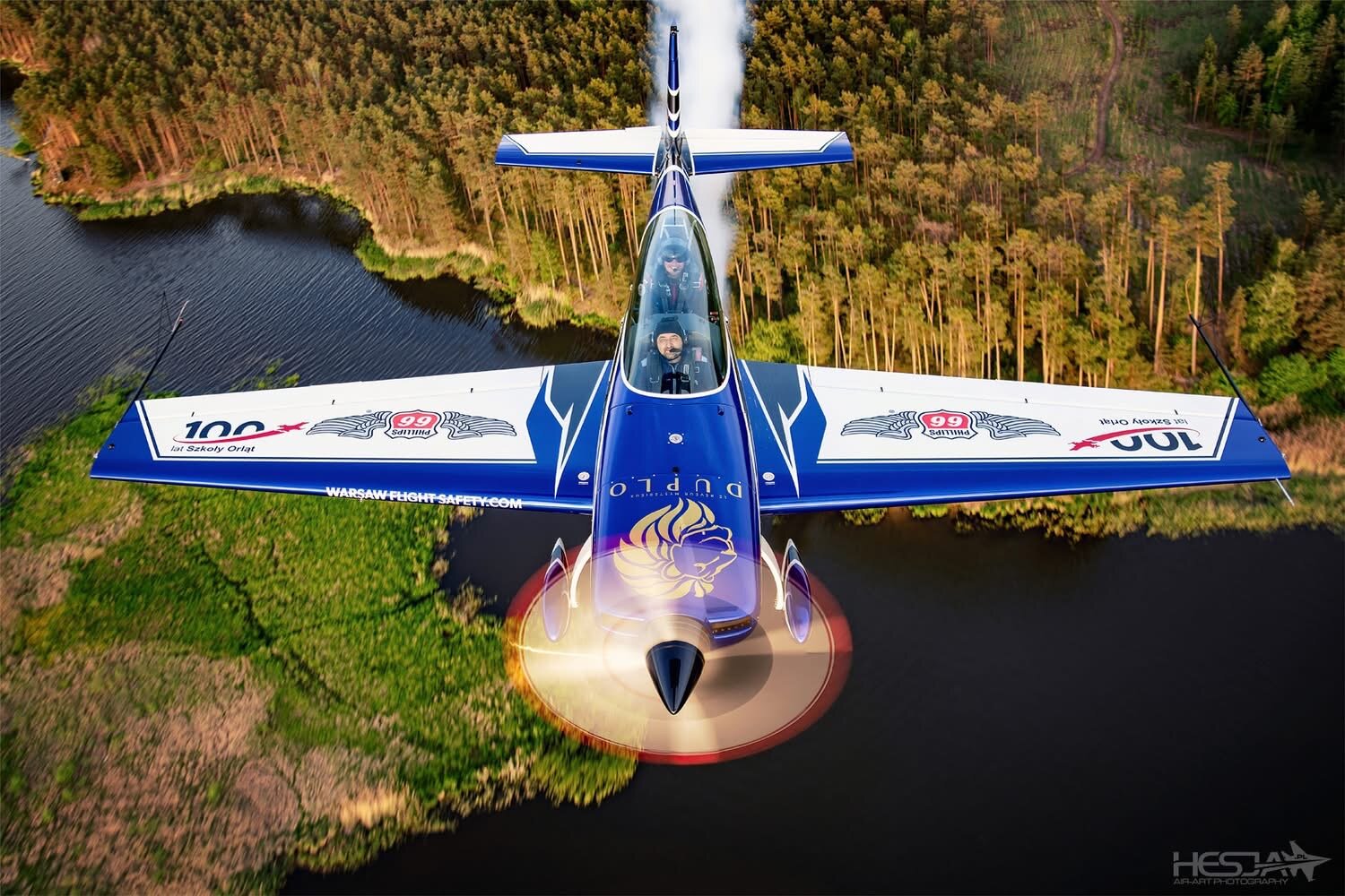Extra 300L SP-EKS from above over a lake and forest