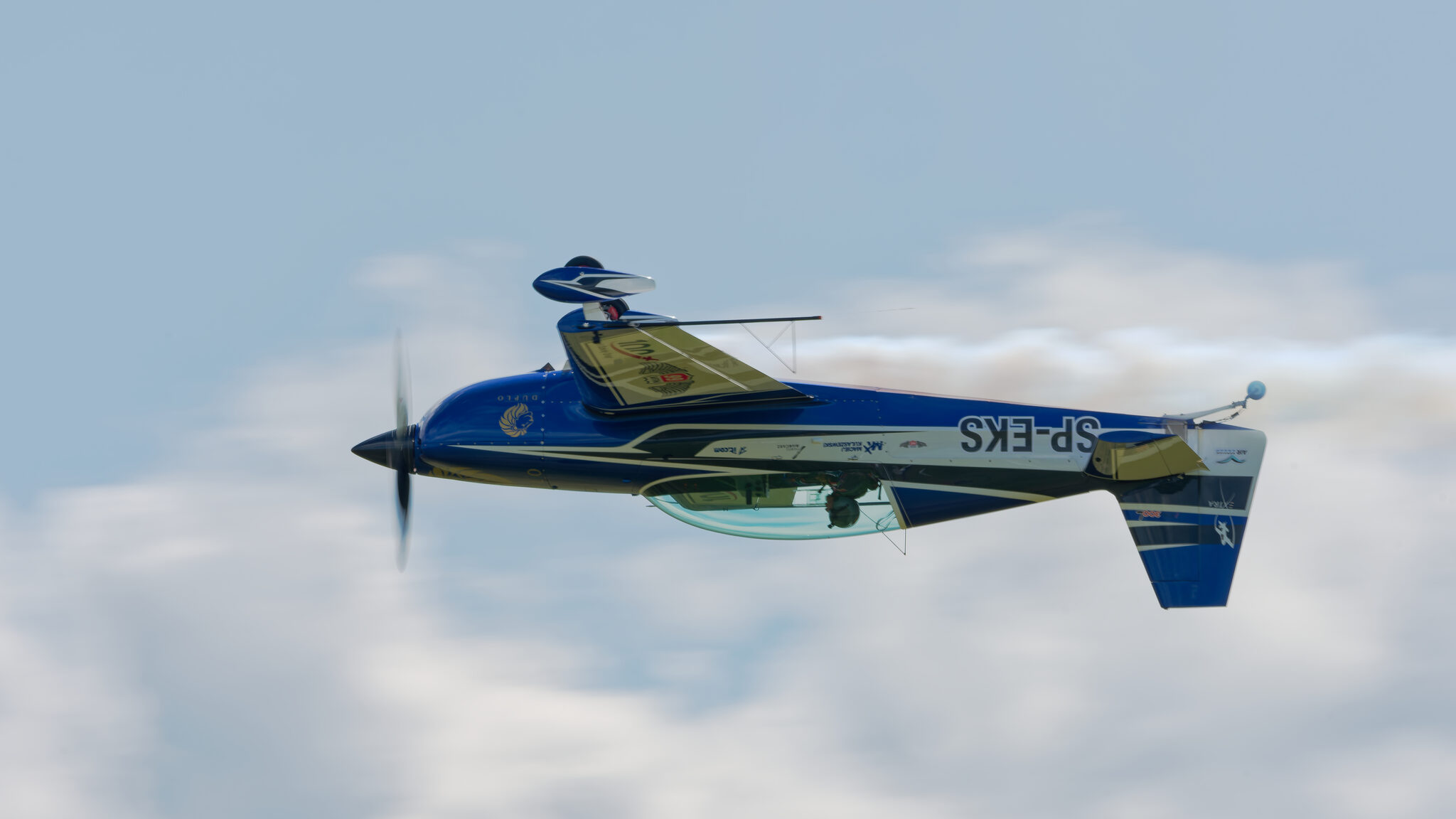 Inverted top-side pass of SP-EKS against the clouds, registration visible